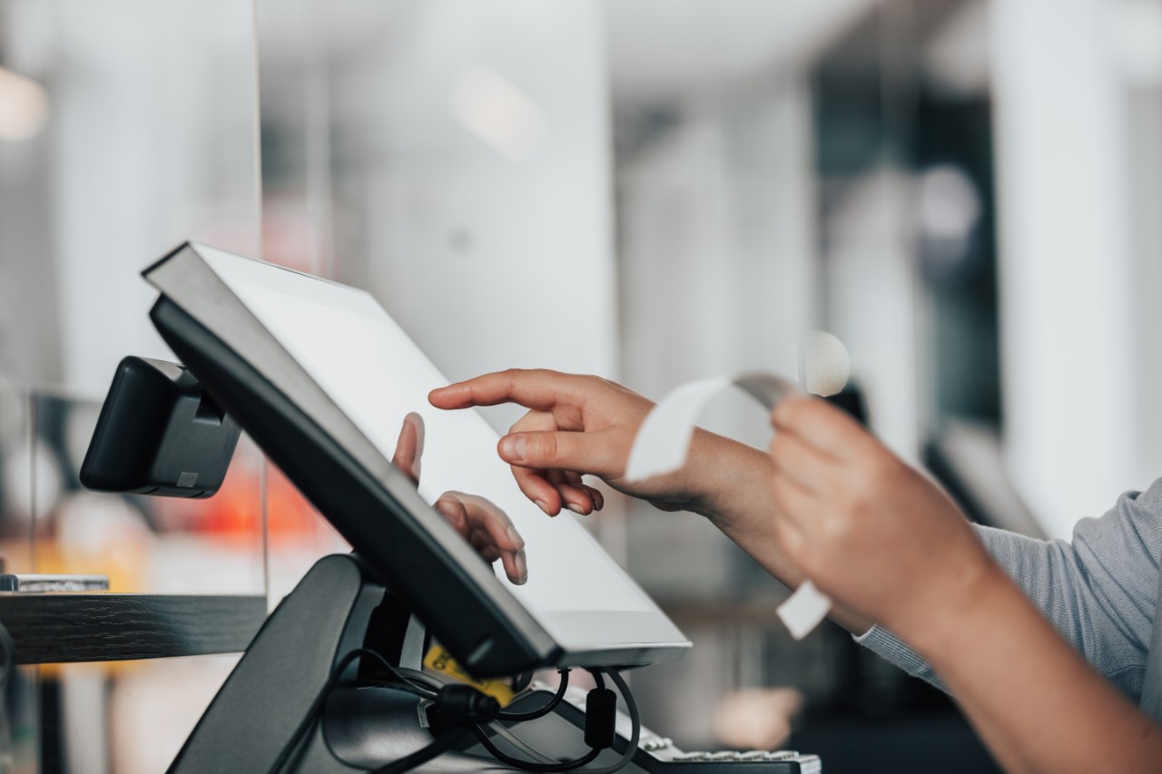 Young saleswoman doing process payment on touchscreen POS, counting sale in the cash register, finance concept Young saleswoman doing process payment on the touchscreen POS, counting sale in the cash register, finance concept