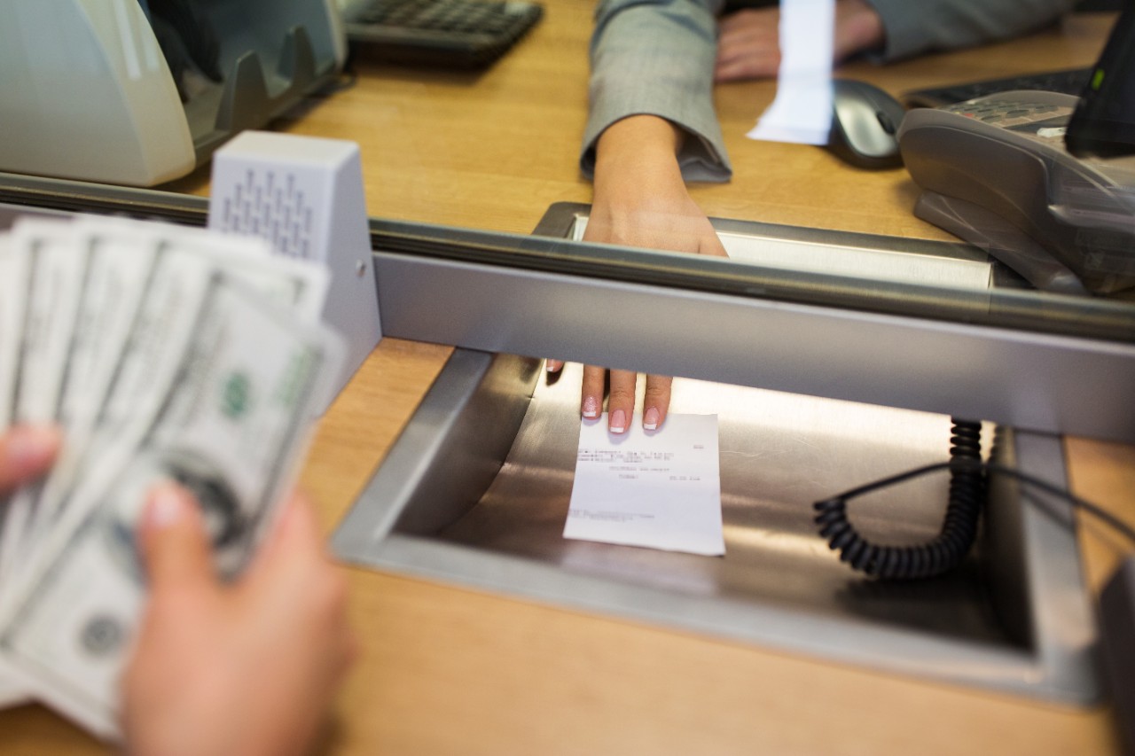 PLS partnership people, withdrawal, saving and finance concept - clerk giving receipt to customer with money at bank office or currency exchanger